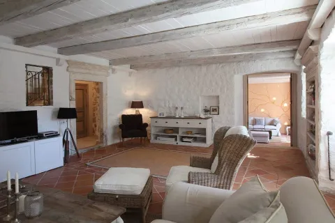 Spacious living room with stone walls, wooden ceiling beams, and traditional furniture. - image 3