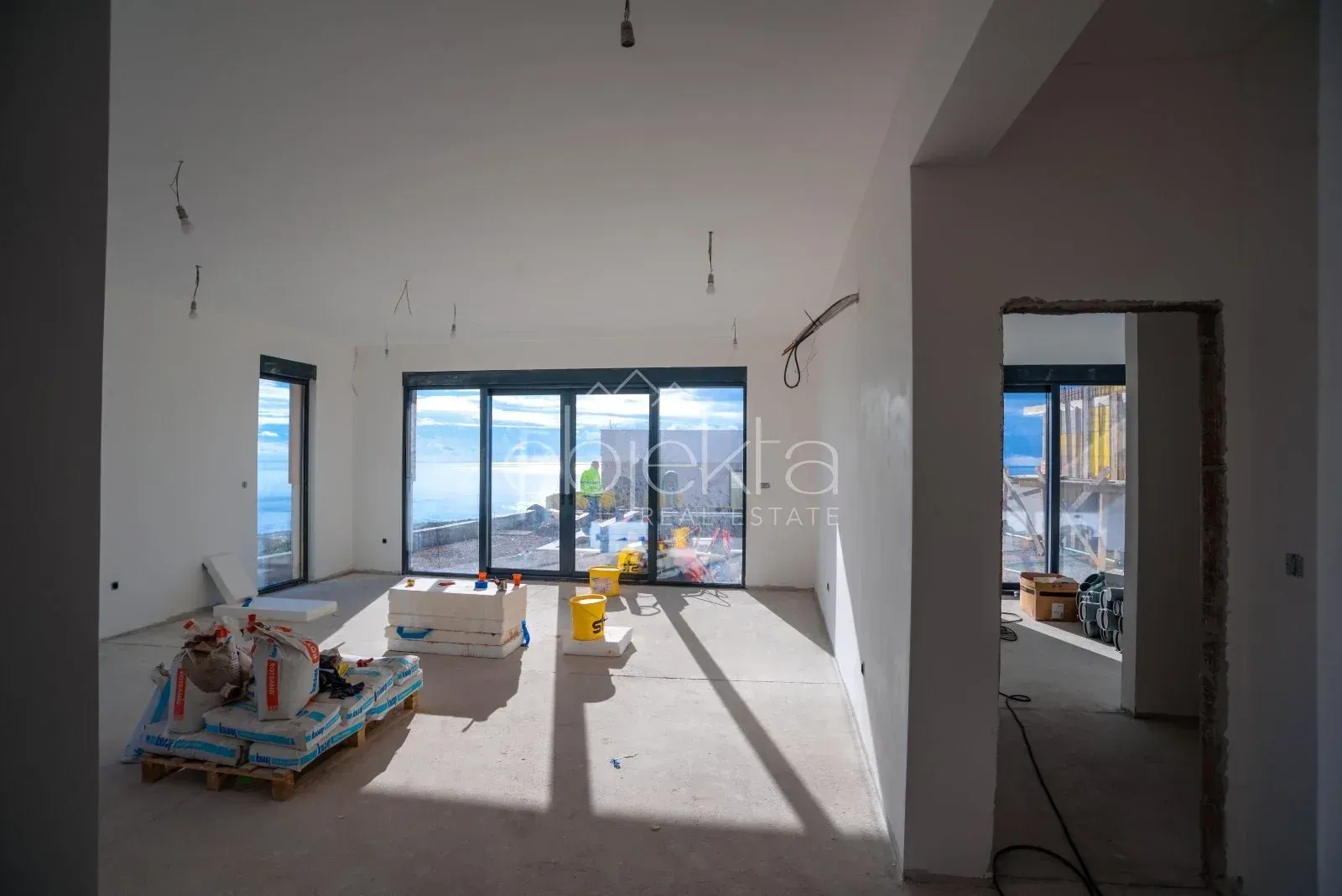 View of a spacious room under construction with large glass surfaces.