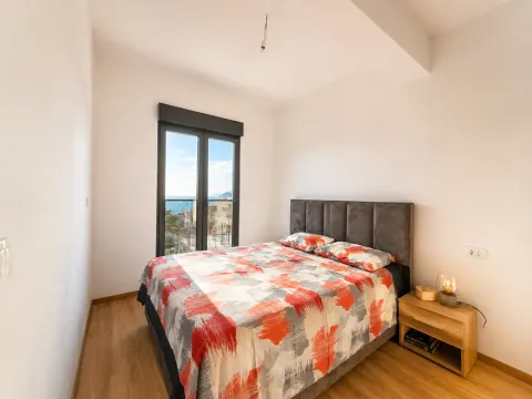 Bright bedroom with a double bed, nightstand, and balcony door offering a sea view. - image 3