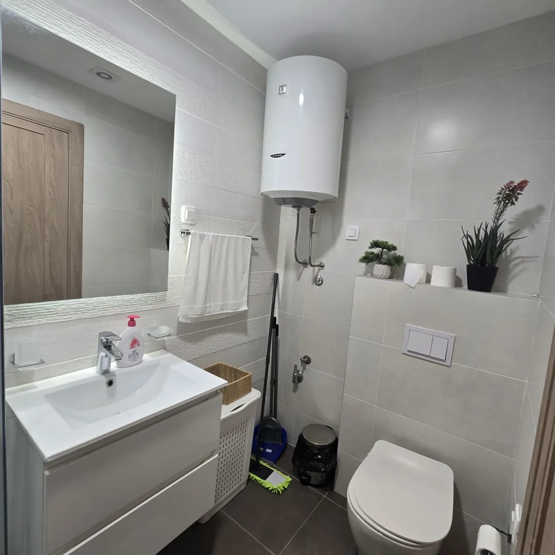 A modernly equipped bathroom with a washbasin, toilet bowl, and water heater.