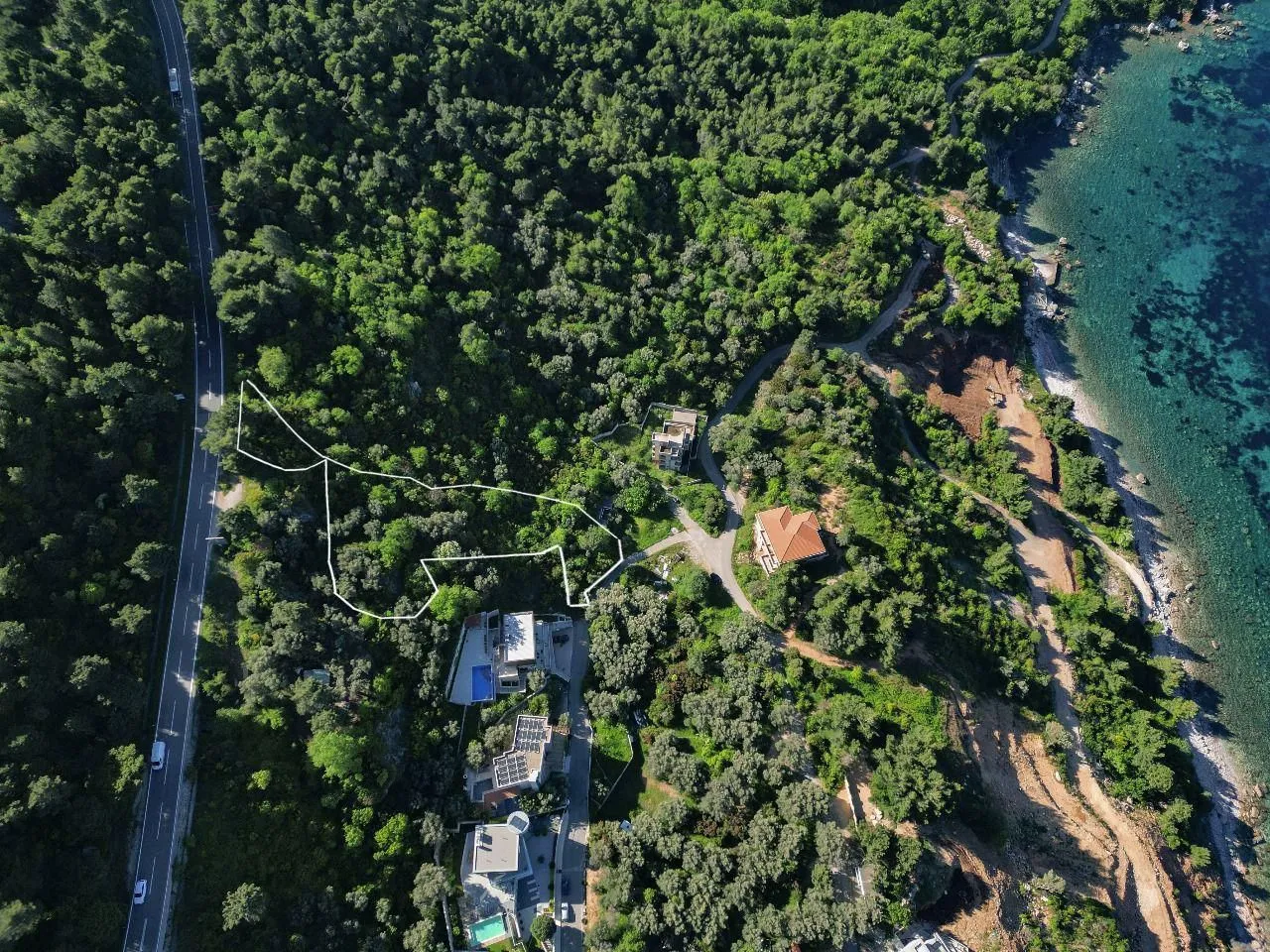 Pogled iz vazduha na parcelu sa označenim granicama u šumovitom području blizu obale.