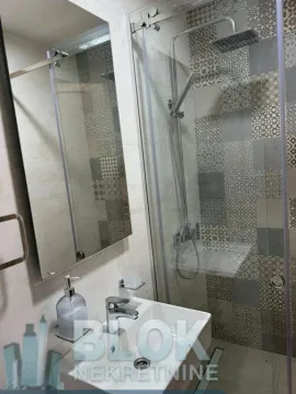 Smaller bathroom with a shower cabin, washbasin, and mirror. - image 5
