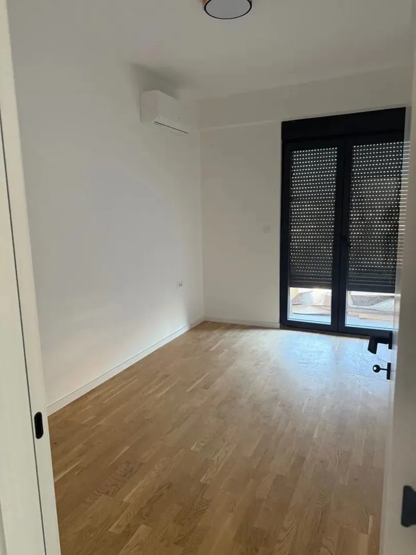Empty room with parquet flooring and balcony doors.