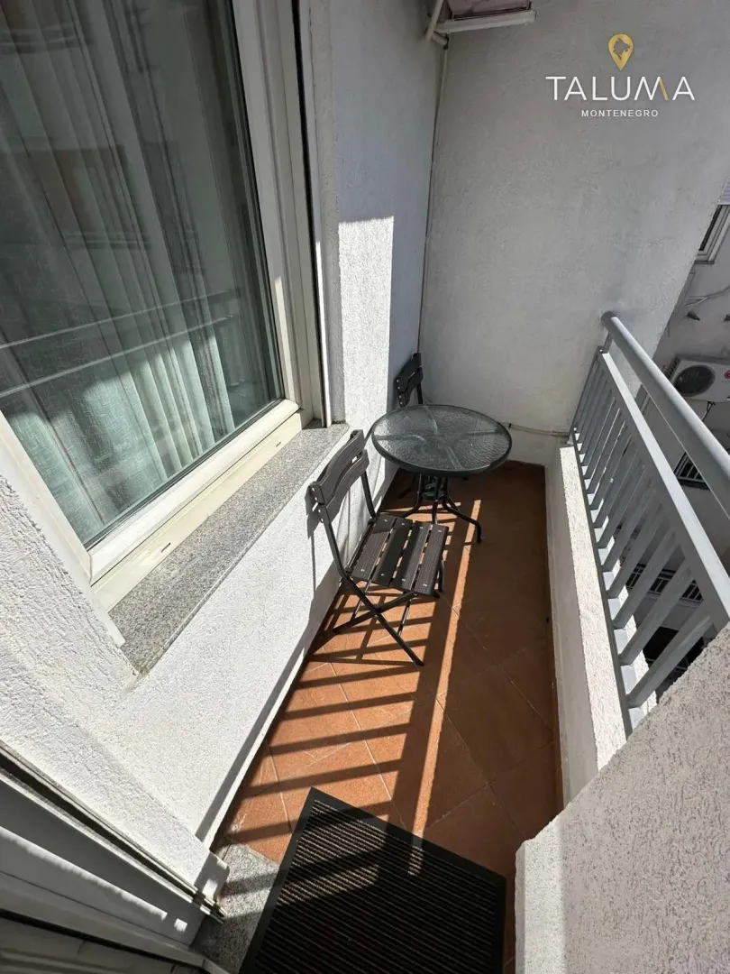 Small balcony furnished with a table and two chairs.