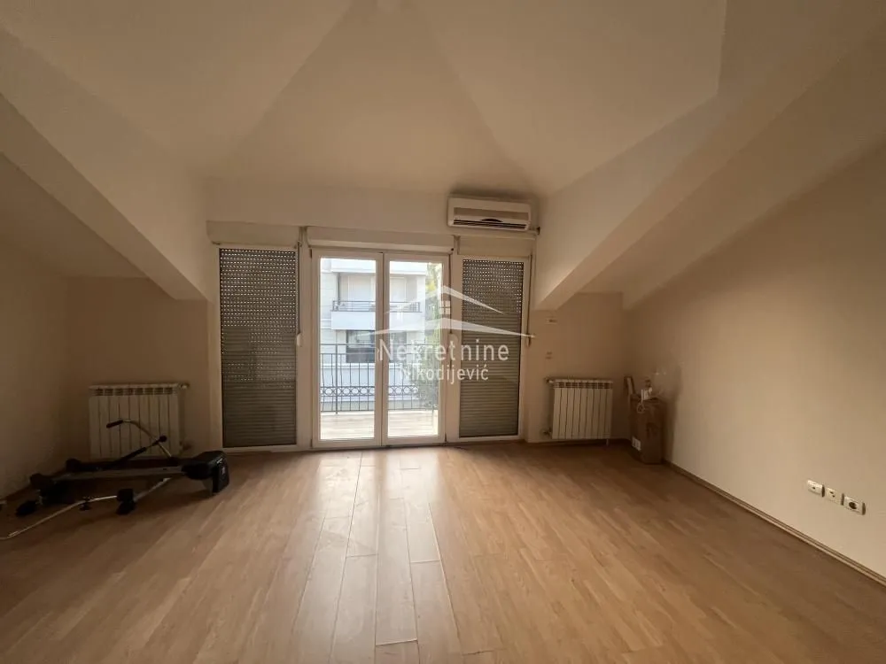 Empty room with wooden flooring, air conditioning unit, and balcony doors.