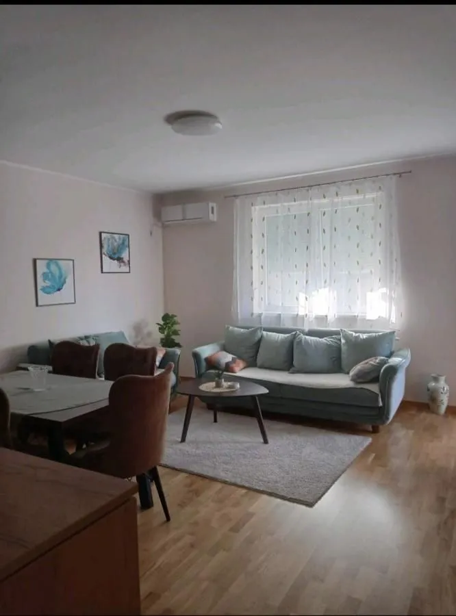 Dnevna soba sa garniturom za sedenje, trpezarijskim stolom i prozorom.