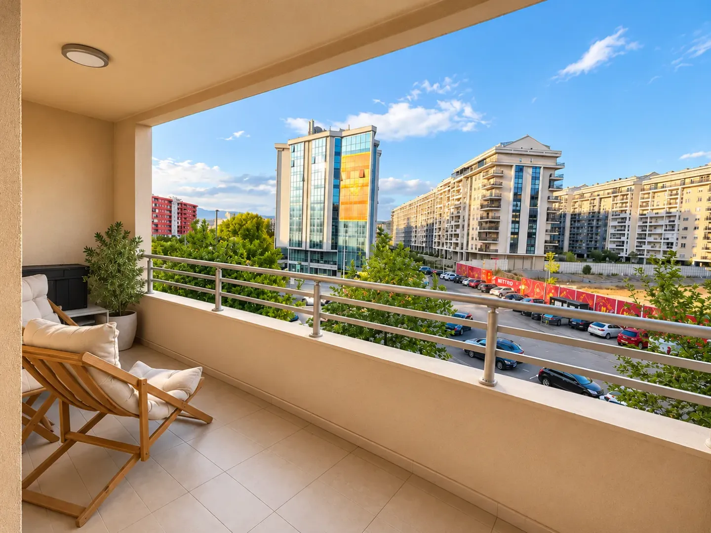Natkriveni balkon sa drvenom foteljom i pogledom na grad.