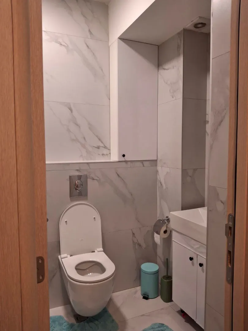 Modern bathroom with marble tiles, toilet, and sink.