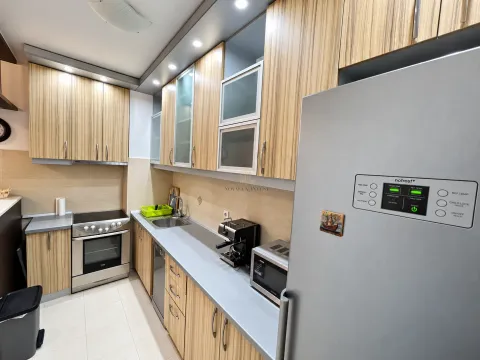 Modern kitchen with wooden cabinetry, built-in appliances, and a large refrigerator. - image 5
