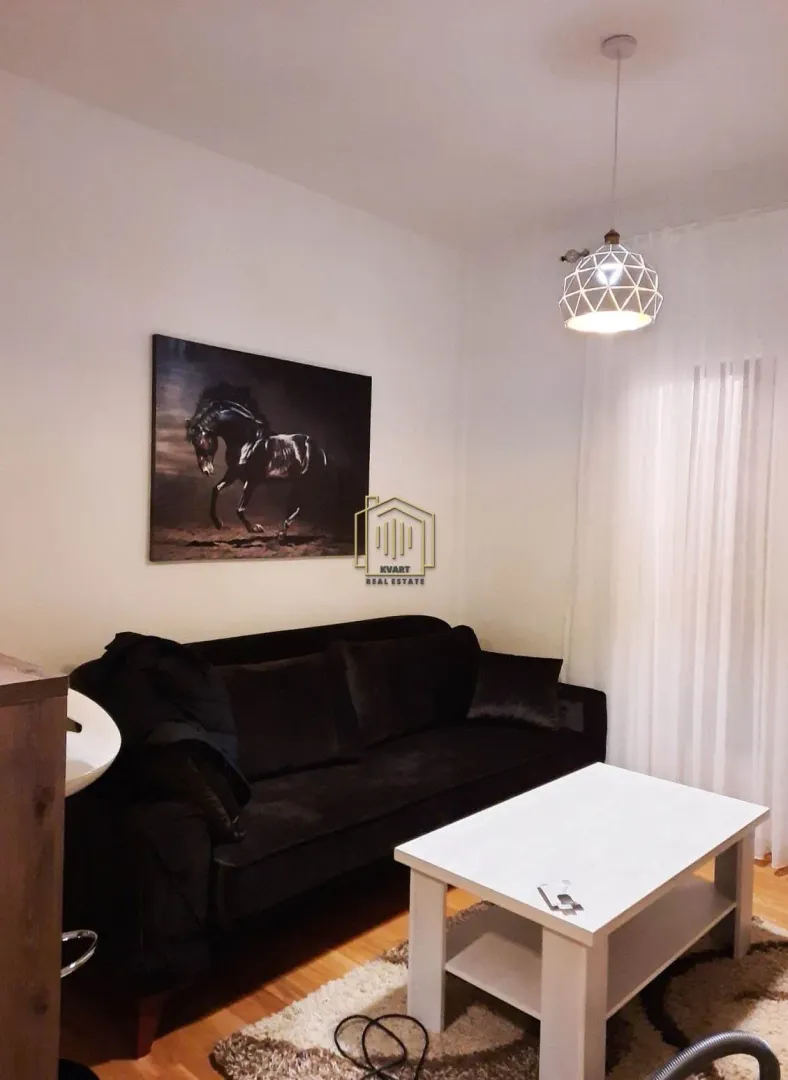 Living room with a black sofa, white coffee table, and a horse painting on the wall.