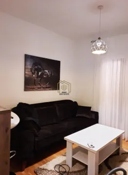 Living room with a black sofa, white coffee table, and a horse painting on the wall. - image 2