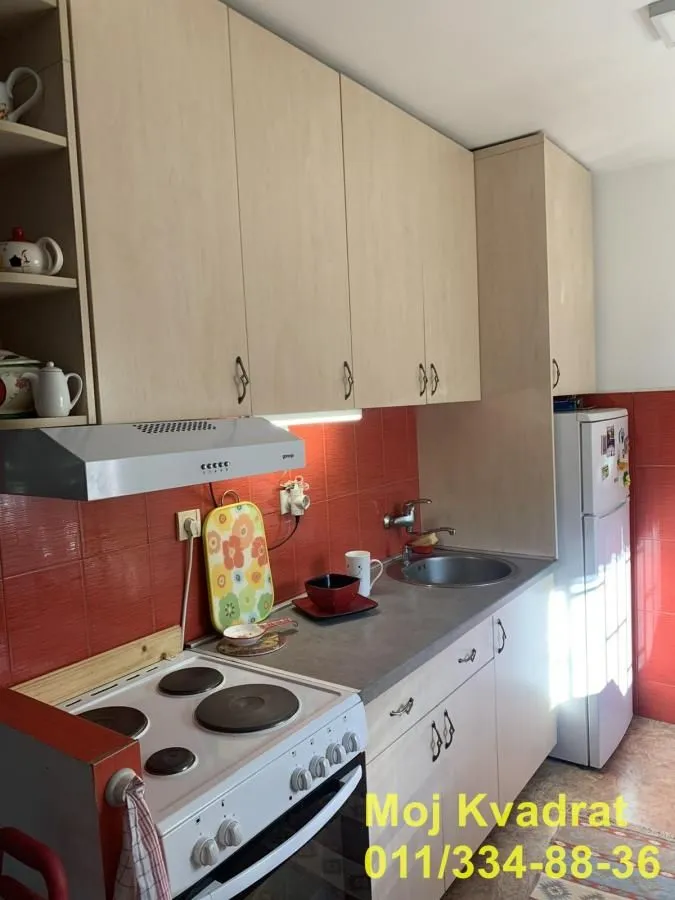 Small kitchen with wooden cabinetry, a white stove, and a refrigerator.