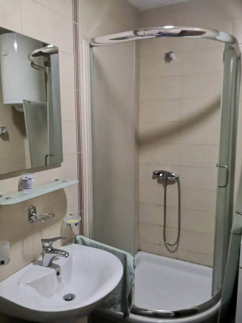 Kupatilo sa tuš kabinom, ogledalom i lavaboom.