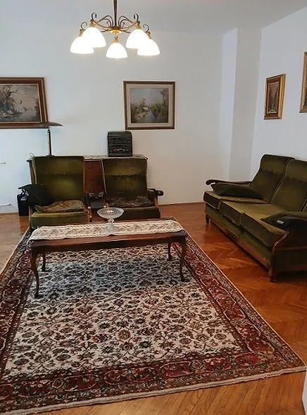 Dnevna soba sa garniturom za sedenje, tepihom i slikama na zidu.