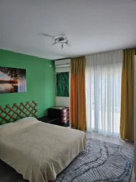 Bedroom with a double bed, green accent wall, and terrace access. - image 4