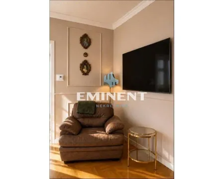 Comfortable armchair with a small side table and a wall-mounted TV in the living room. - image 4