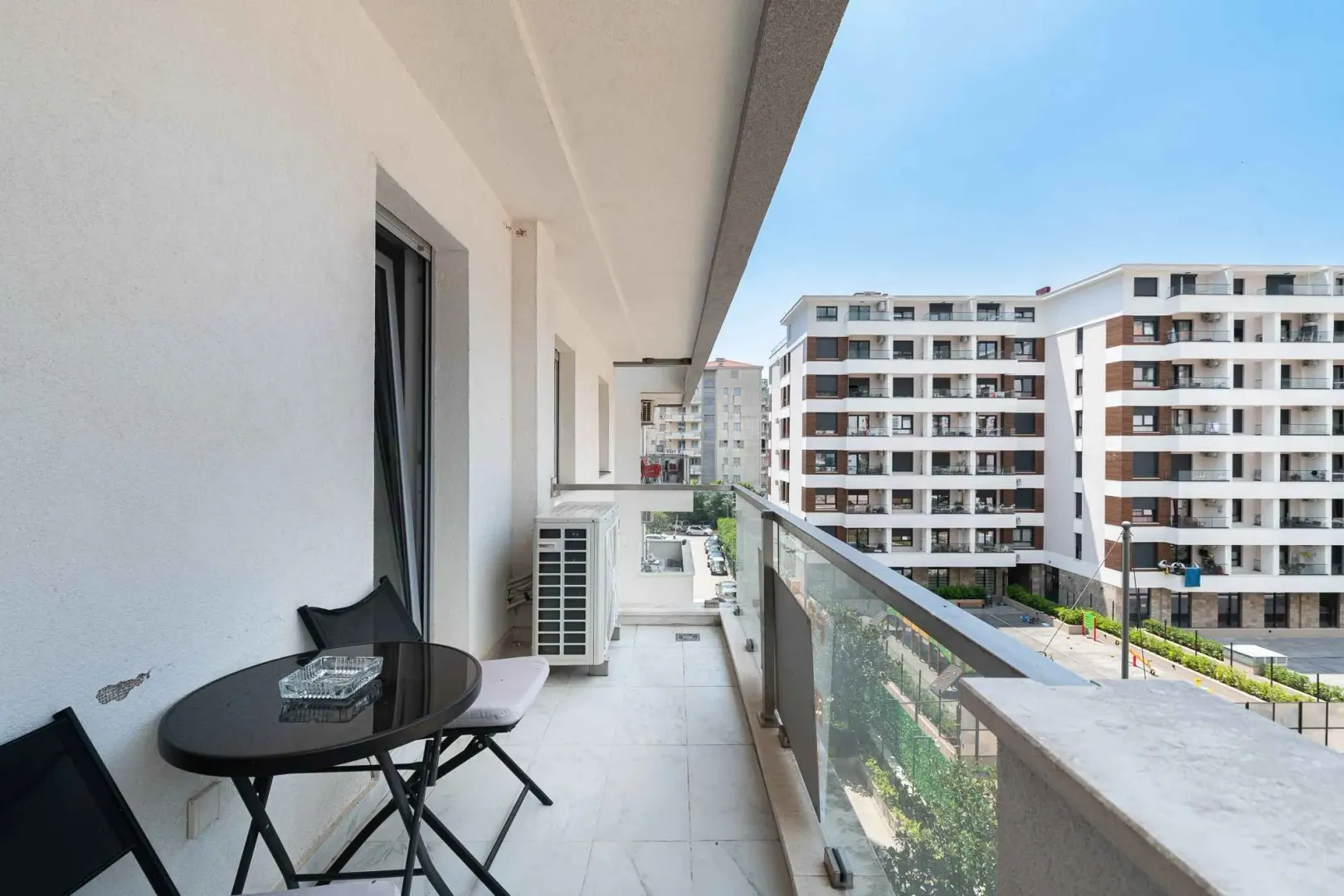 Spacious covered balcony with a table and chairs overlooking buildings.