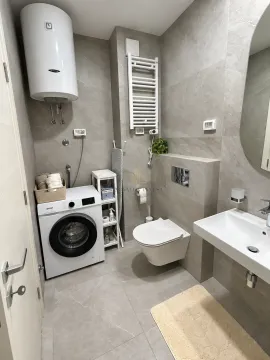 A modern bathroom equipped with a shower, washing machine, and water heater. - image 7