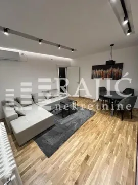 Living room with a sofa, dining table, and hardwood flooring. - image 2