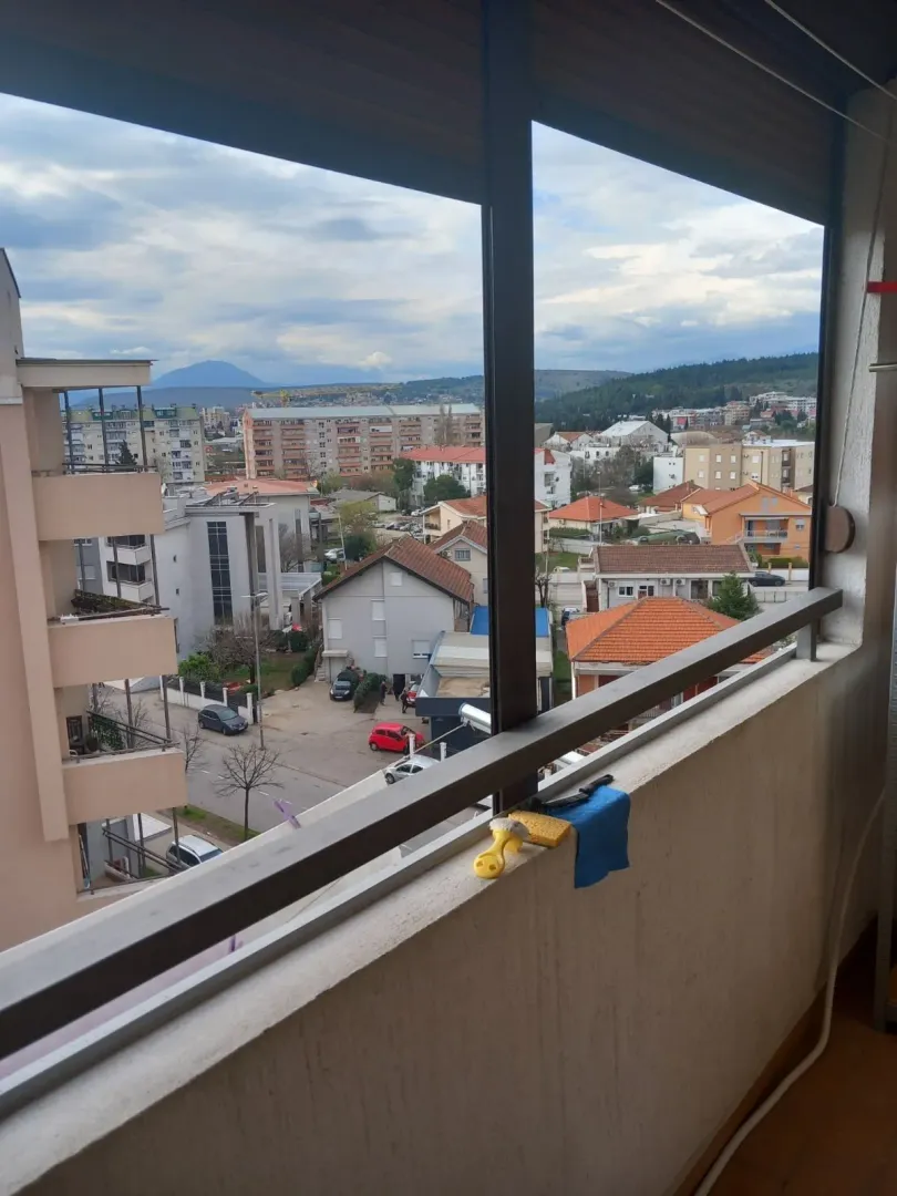 Pogled sa terase stana na naselje i brda u daljini.