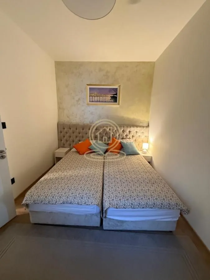 Spavaća soba sa bračnim krevetom i noćnim stočićima.