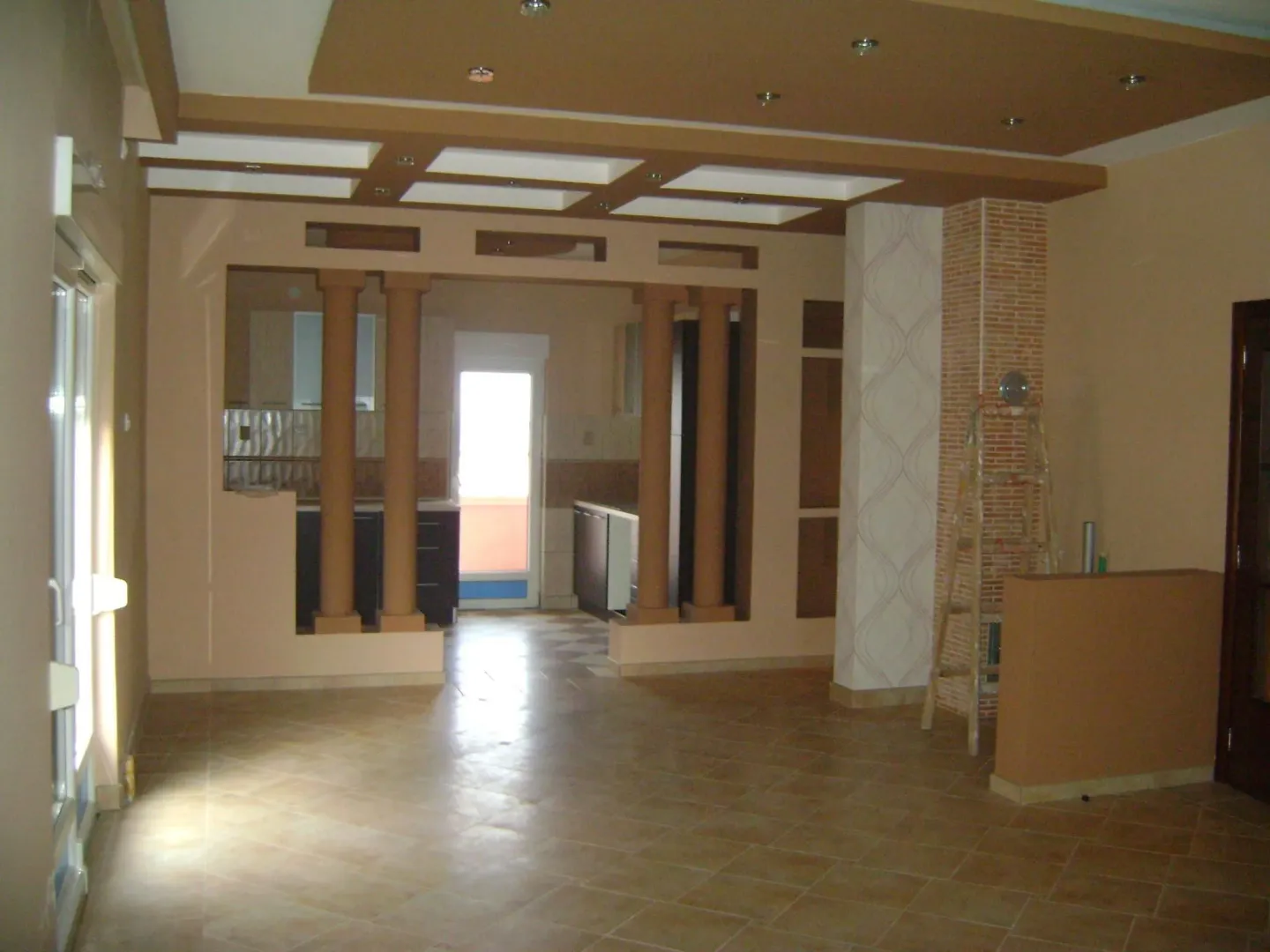 A spacious empty room featuring decorative columns and a suspended ceiling.
