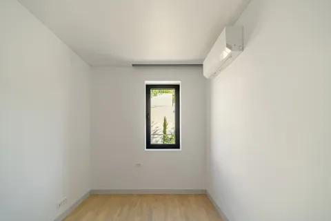 Prazna soba sa bijelim zidovima, drvenim podom, prozorom i klima uređajem. - image 13