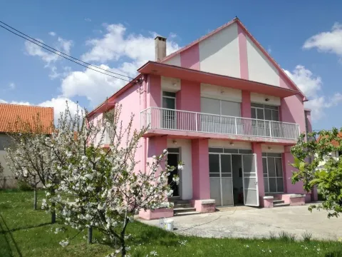 Dvospratna kuća roze boje sa dvorištem i procvjetalim drvetom. - image 5