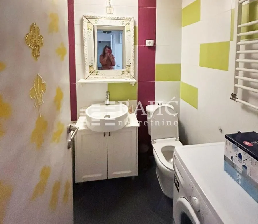Smaller bathroom with a washbasin, toilet, and washing machine.