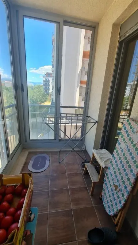 Manji zastakljeni balkon sa keramičkim pločicama na podu i staklenim vratima.