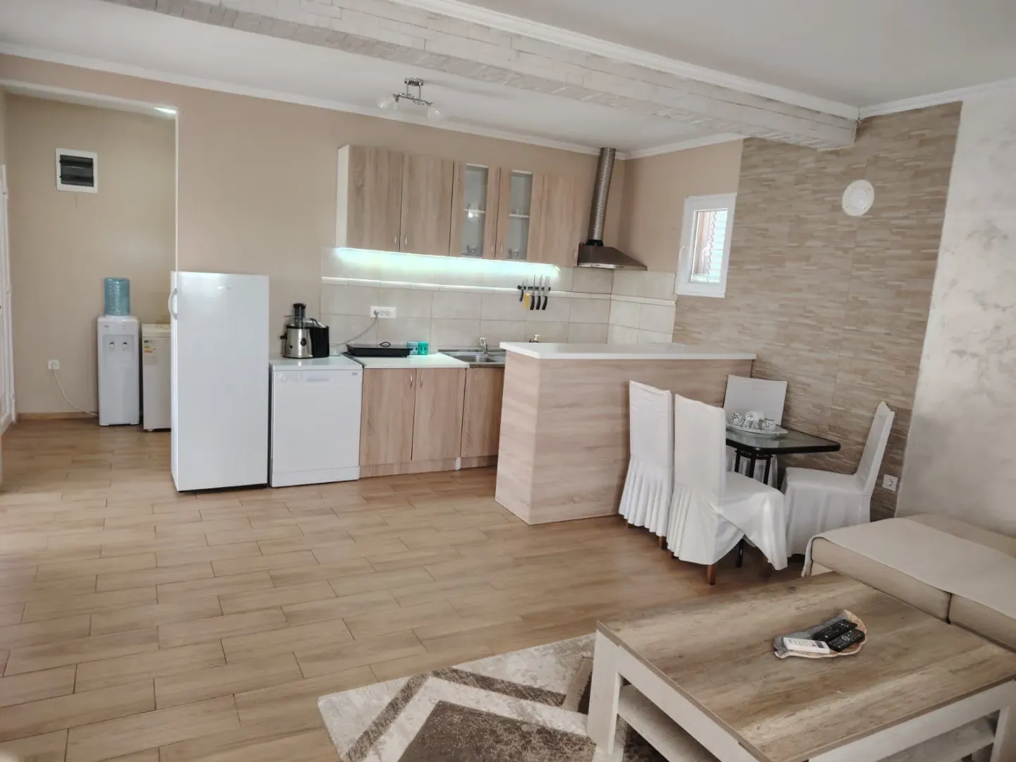 Living room with kitchen and dining area in bright tones.