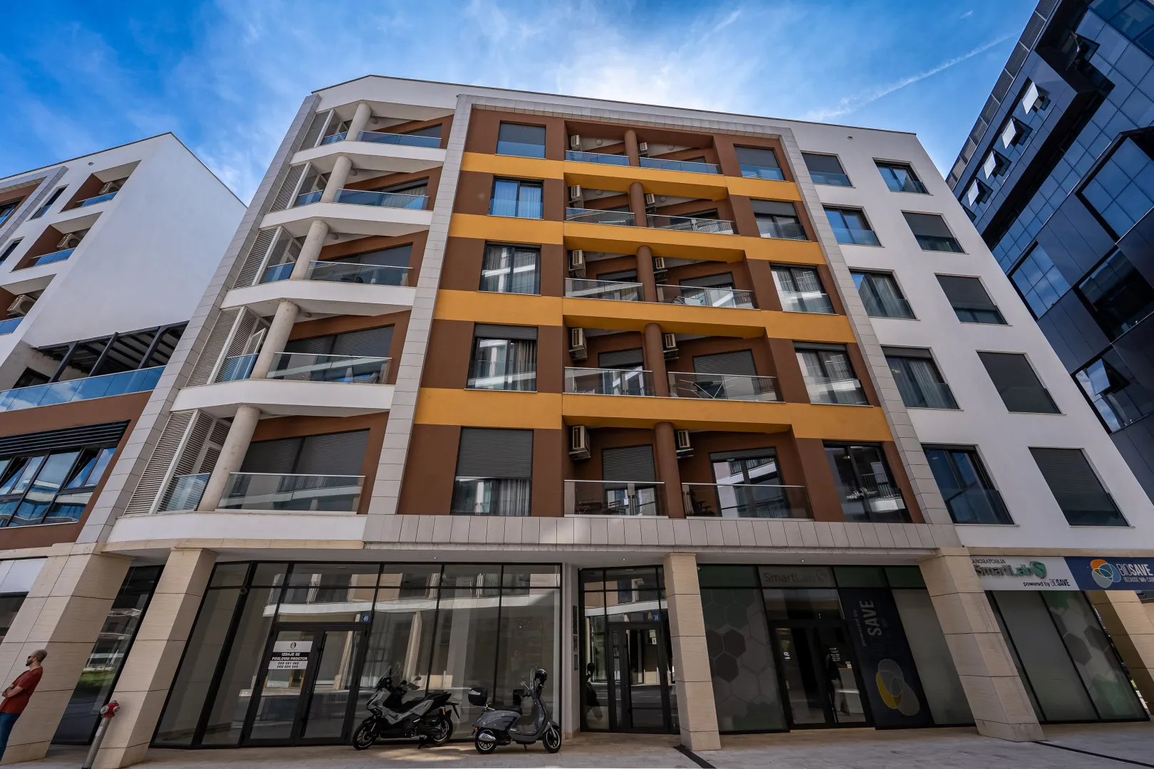 View of a modern residential and commercial building with balconies and ground floor retail space.