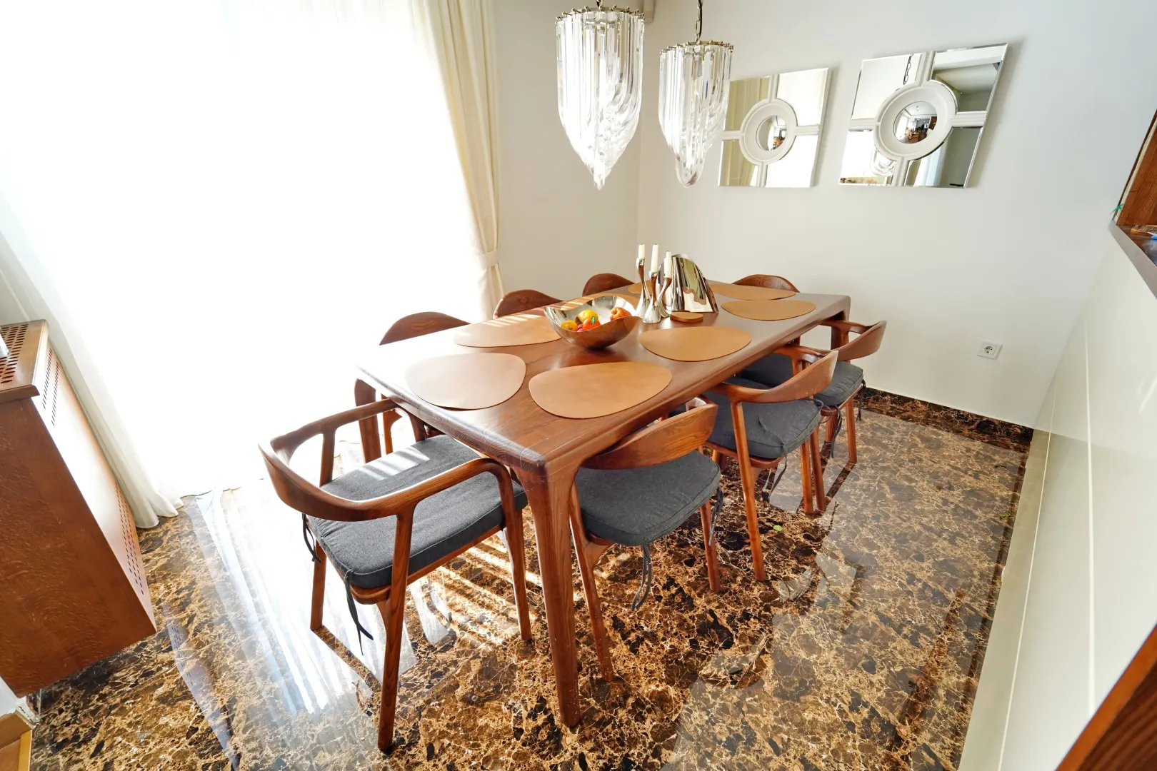 Dining room with a wooden table, chairs, and chandeliers.