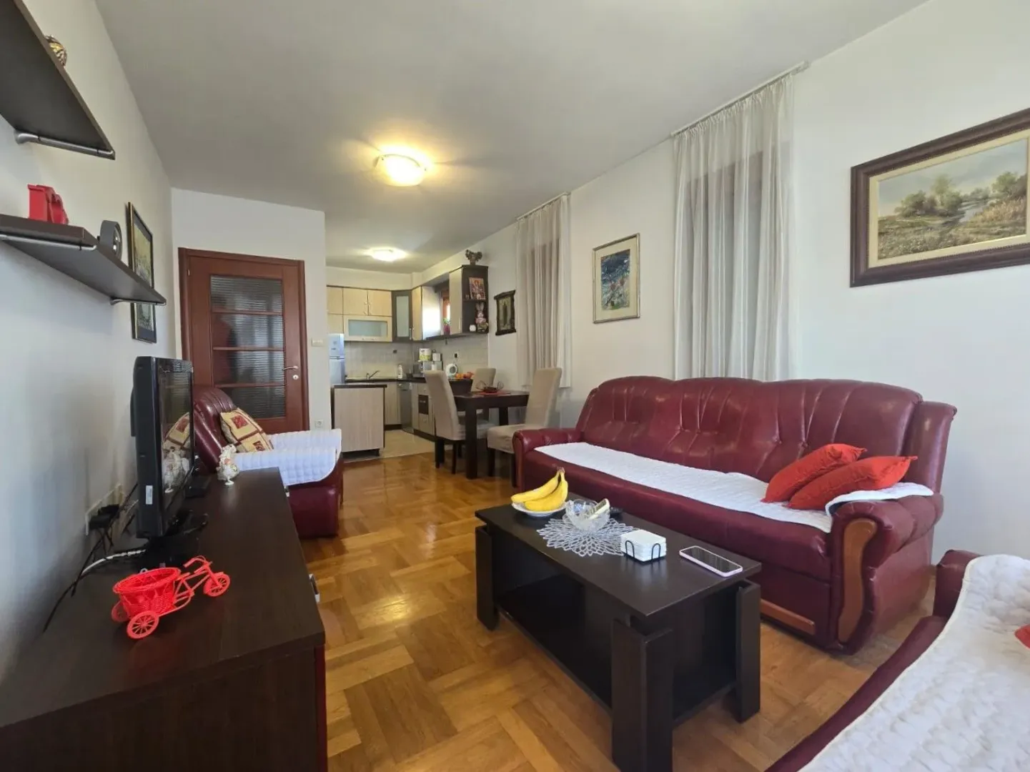 Dnevni boravak sa garniturom i trpezarijom u pozadini.