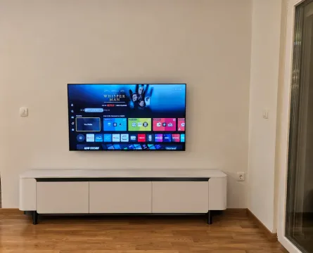 Living room with a wall-mounted TV and a white TV stand. - image 5
