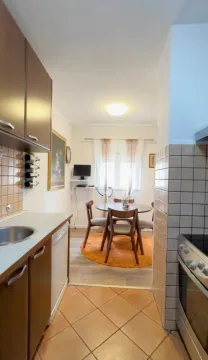Small kitchen with a dining area and a wooden table. - image 5