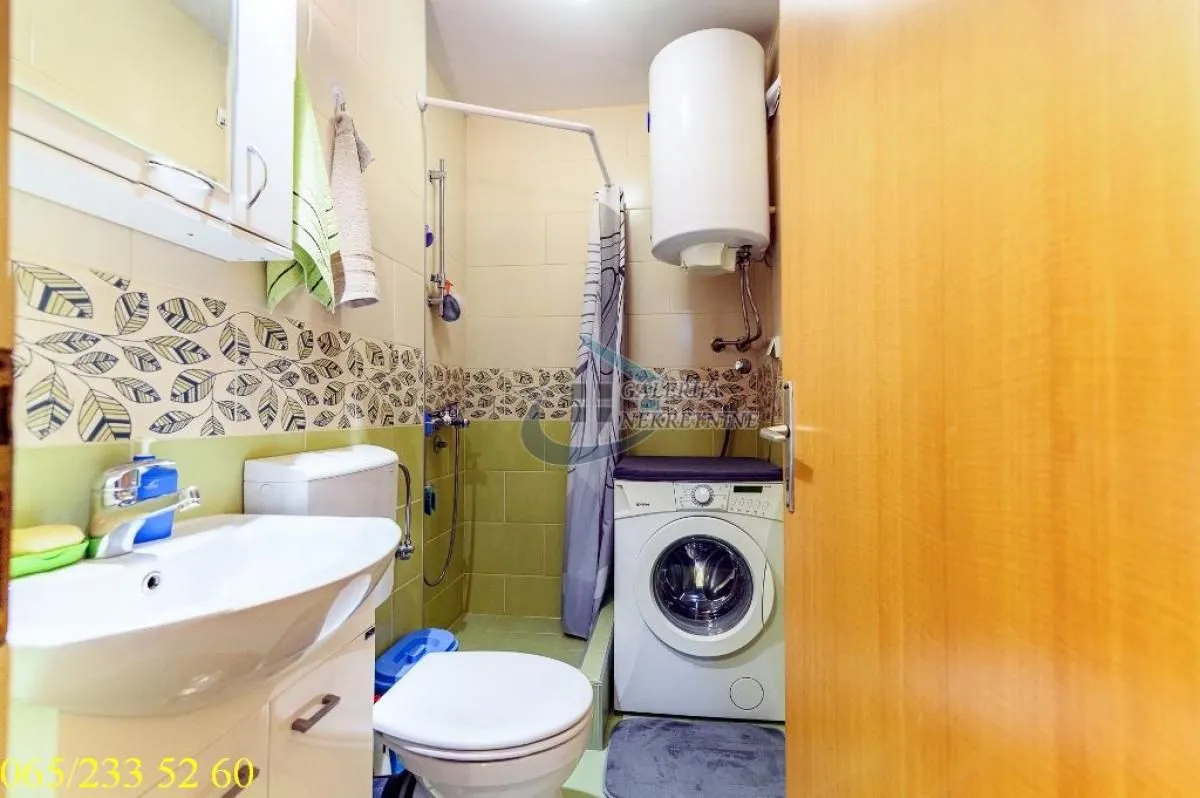 Smaller bathroom with a washbasin, toilet, shower and washing machine.
