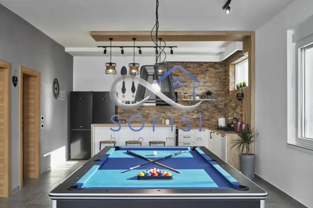 Living room with a pool table and an open kitchen in the background.