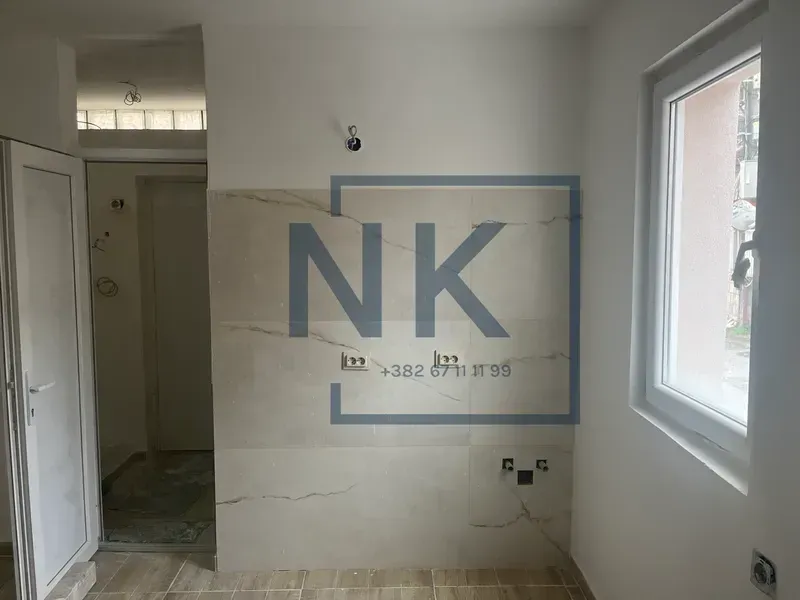 Pogled na dio prostorije u izgradnji sa keramičkim pločicama na zidu i prozorom.