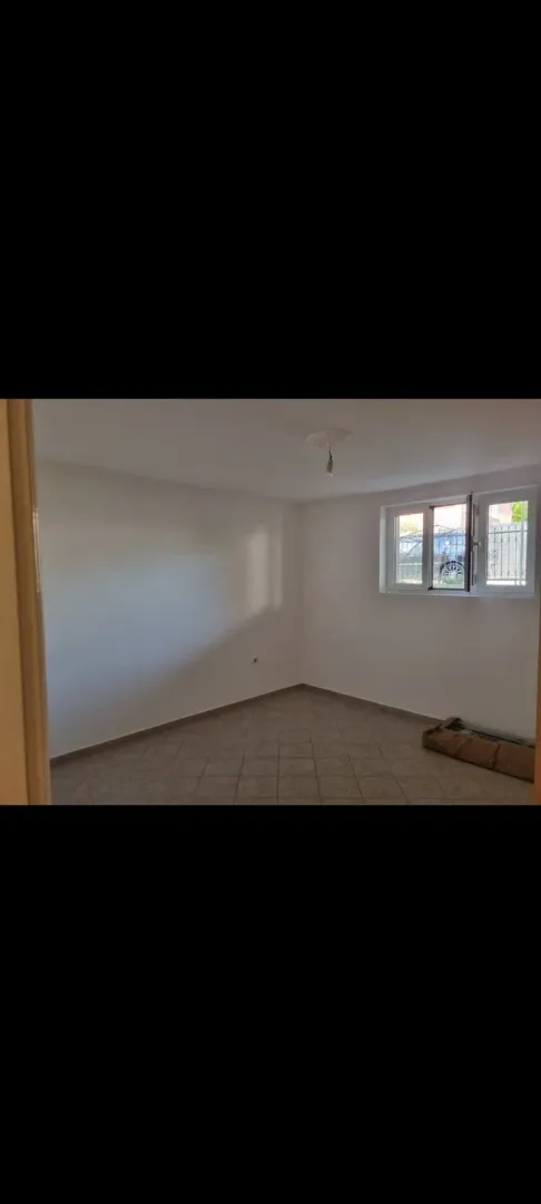 An empty room with tiled flooring and a single window.