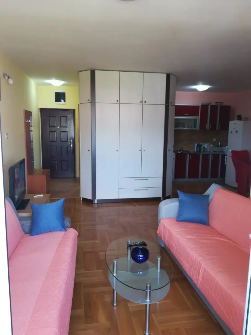 Furnished living room with a seating area and kitchen in the background.