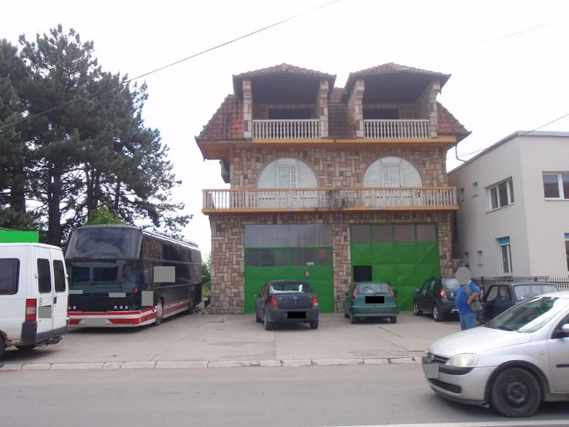 Exterior view of a multi-story house with a yard and parked vehicles.