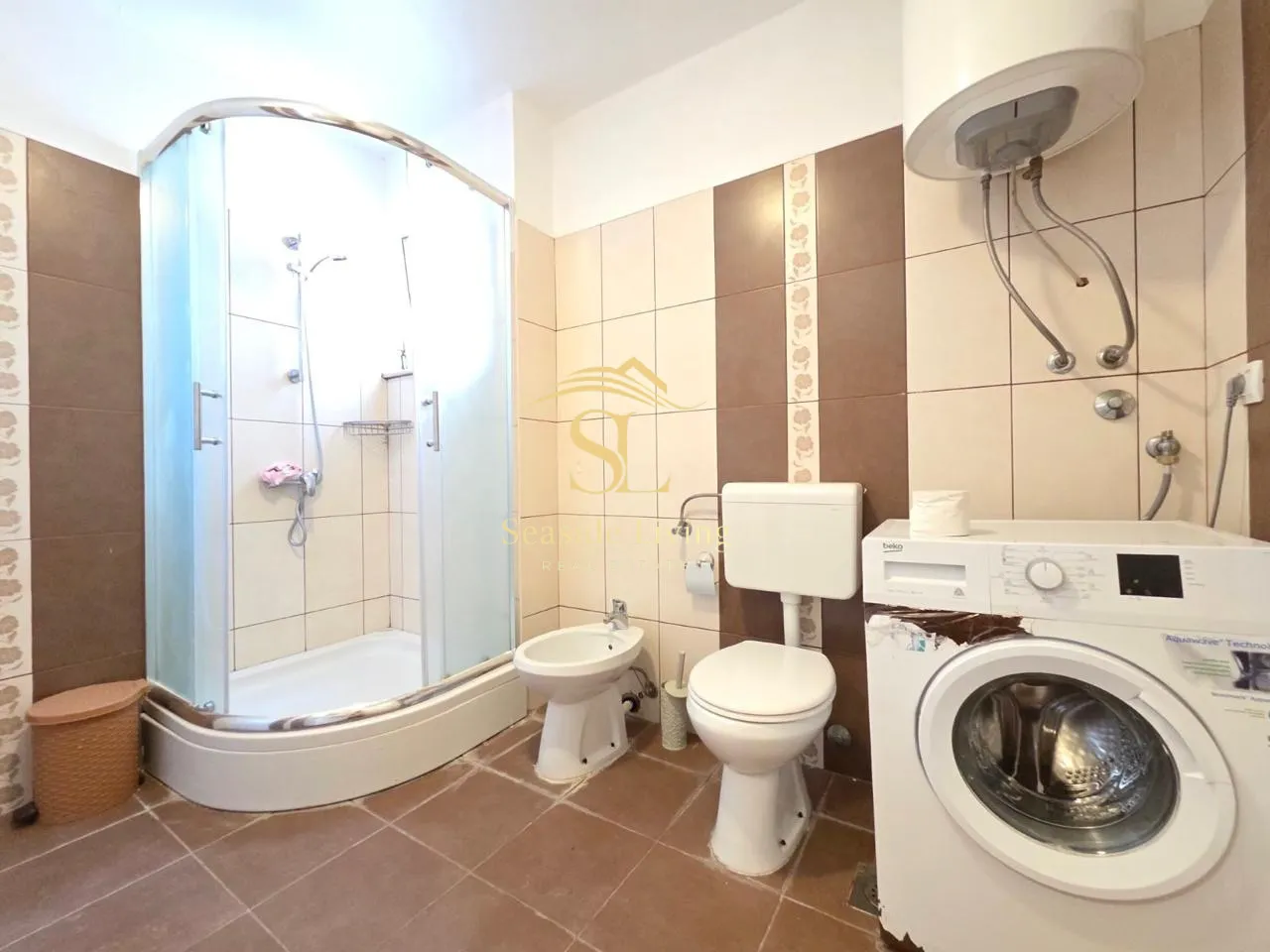 Small equipped bathroom with a shower cabin and a washing machine.
