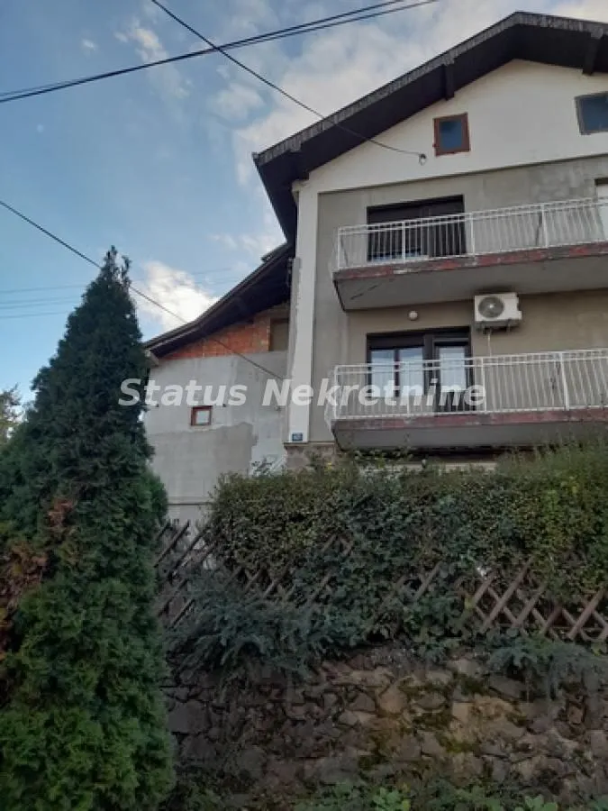 Pogled na spoljašnjost kuće sa dvorištem i balkonima.