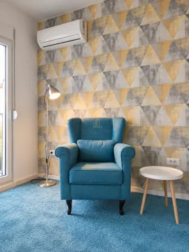 Comfortable armchair with a small table and decorative wallpaper in the room. - image 3