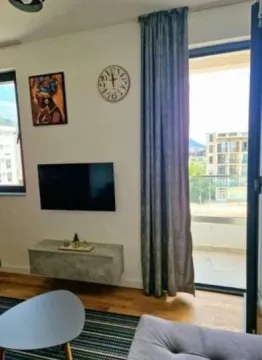Dnevna soba sa televizorom, zidnim satom i izlazom na terasu. - image 8