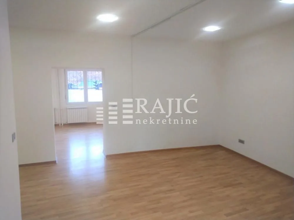 Empty room with parquet flooring and a view into another room.