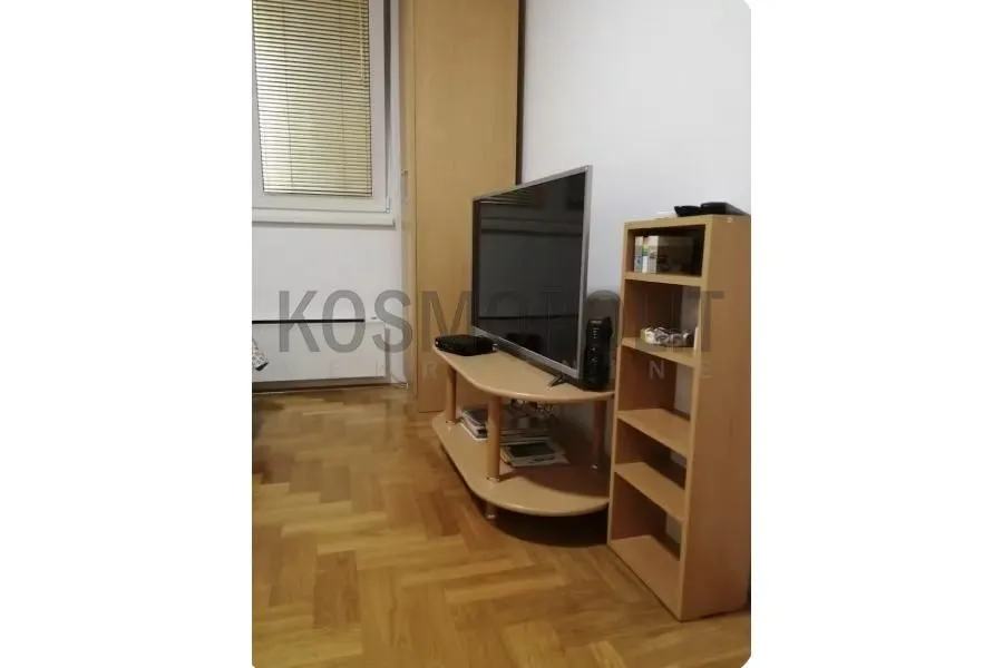 Dnevni boravak sa televizorom i drvenim nameštajem.