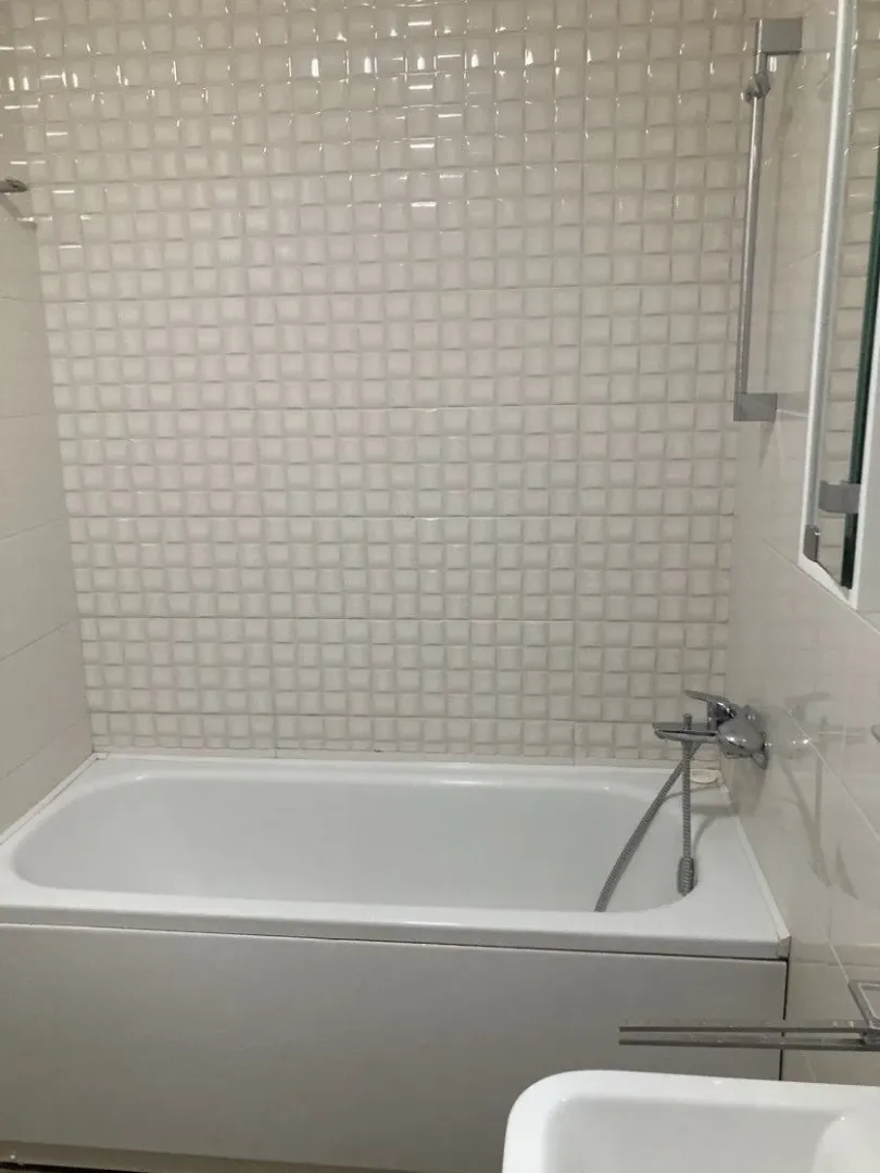 Compact bathroom with a bathtub and white ceramic tiles.