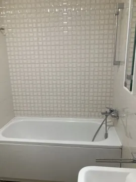 Compact bathroom with a bathtub and white ceramic tiles. - image 8